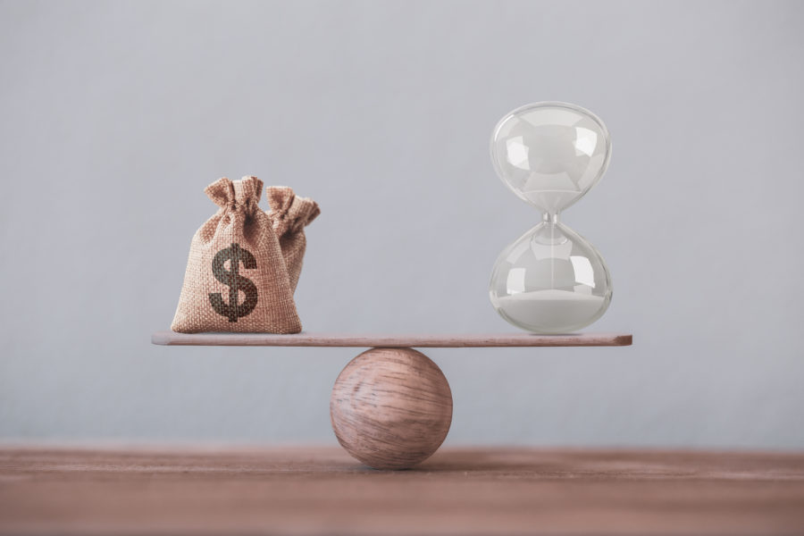 Financial concept : Write sand clock or hourglass symbol and dollar bagson a balance scale in equal position.Time value of money, asset growth over time, investment in long-term equity for more money