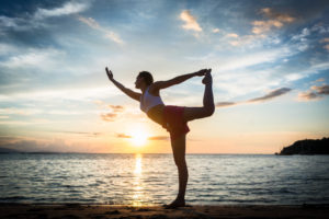person doing sunrise yoga on the beach