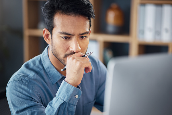 Serious, business man and thinking on computer in office, internet